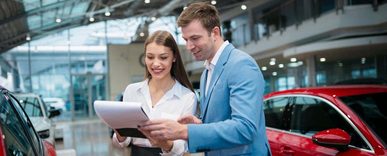 Businessman looking at documents at an automobile dealership.