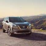 A 2021 Nissan Rogue parked on a mountain top with a city skyline in the valley_mobile