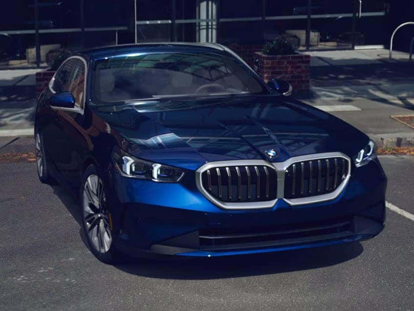 Front view of a blue BMW 5 Series sedan parked outdoors.