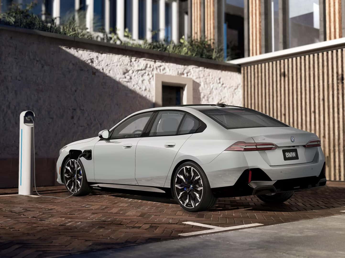 BMW 550e plug-in hybrid sedan charging at a home charging station.