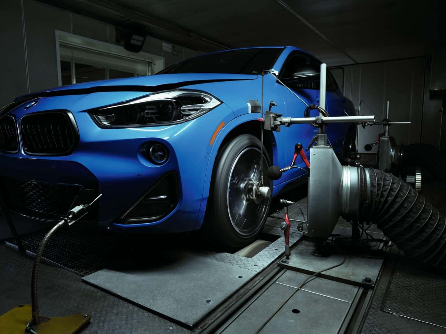 BMW X2 undergoing performance and durability testing on a rolling dynamometer with high-tech sensors.