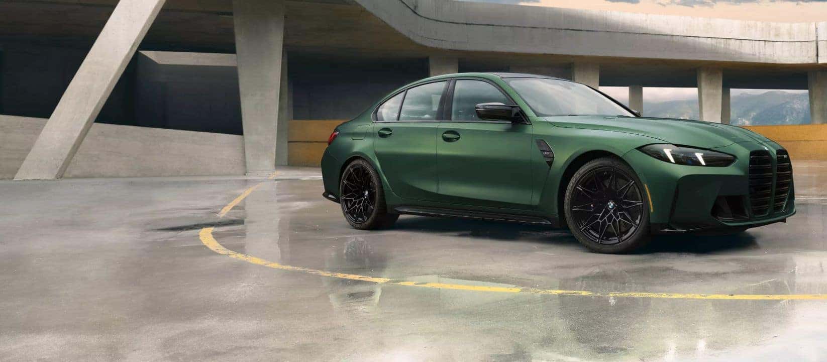 2025 BMW 3 Series M model in matte green paint, showcasing aggressive front design and black wheels.