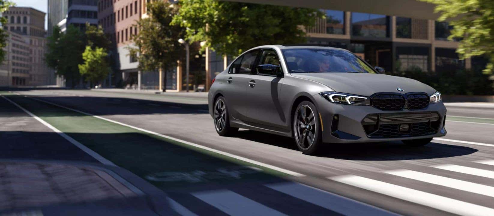 2025 BMW 3 Series M340i driving through a city street, demonstrating its sporty styling and performance.