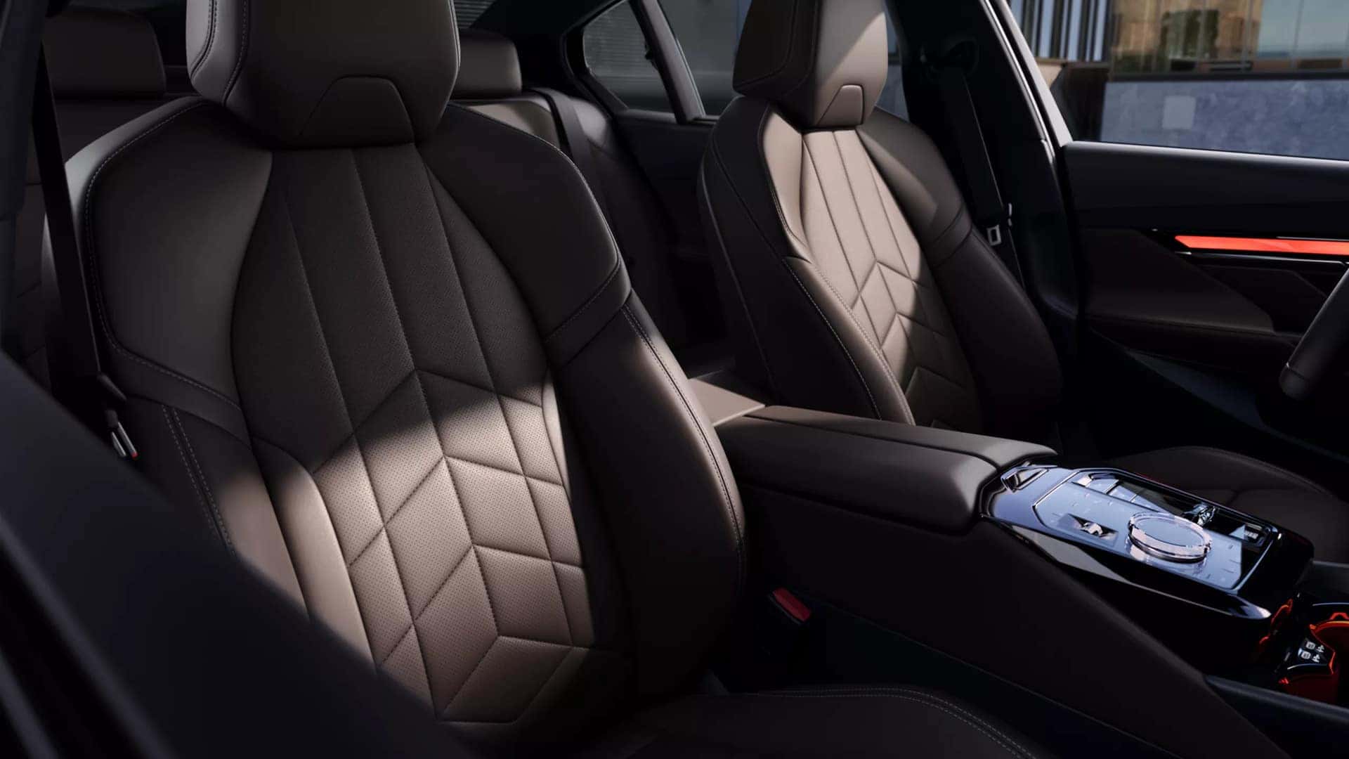 Close-up of luxurious BMW 5 Series front seats with geometric stitching and ambient lighting accents