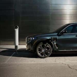 2026 BMW X5 plug-in hybrid charging at a public station in an urban setting