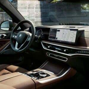 Driver’s view of the 2026 BMW X5 dashboard and touchscreen navigation interface in a brown interior