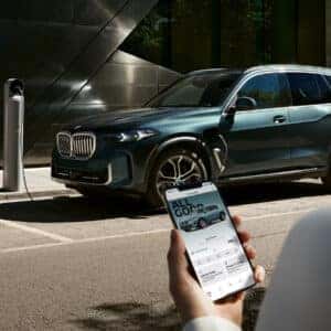 2026 BMW X5 plug-in hybrid connected to a charging station while monitored via mobile app