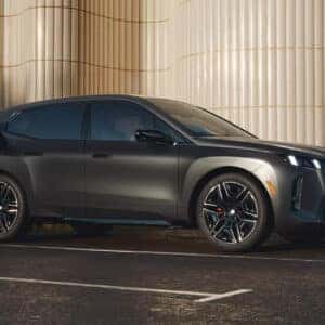 teh side profile of a 2026 bmw ix in a metallic dark gray parked in a parking spot charging