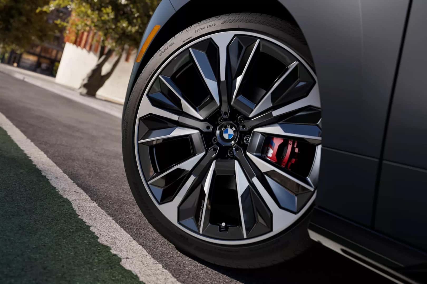 up close of the driver's tire on a bmw ix m70 showcasing the red brake calipers
