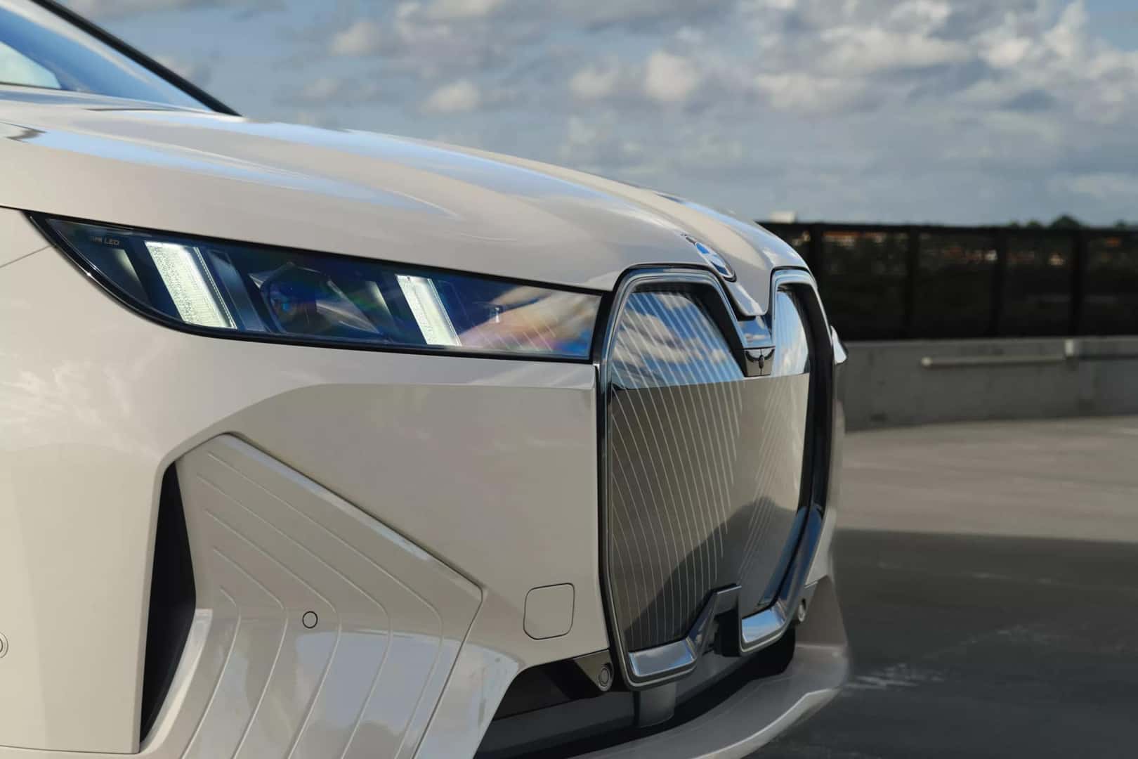 front side profile of a cream 2026 bmw ix showcasing the kidney grille and headlights.