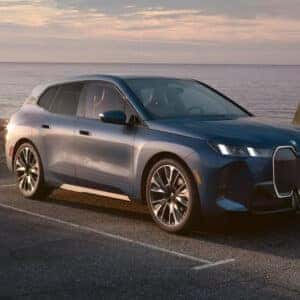 a 2026 bmw ix parked next to a body of water.