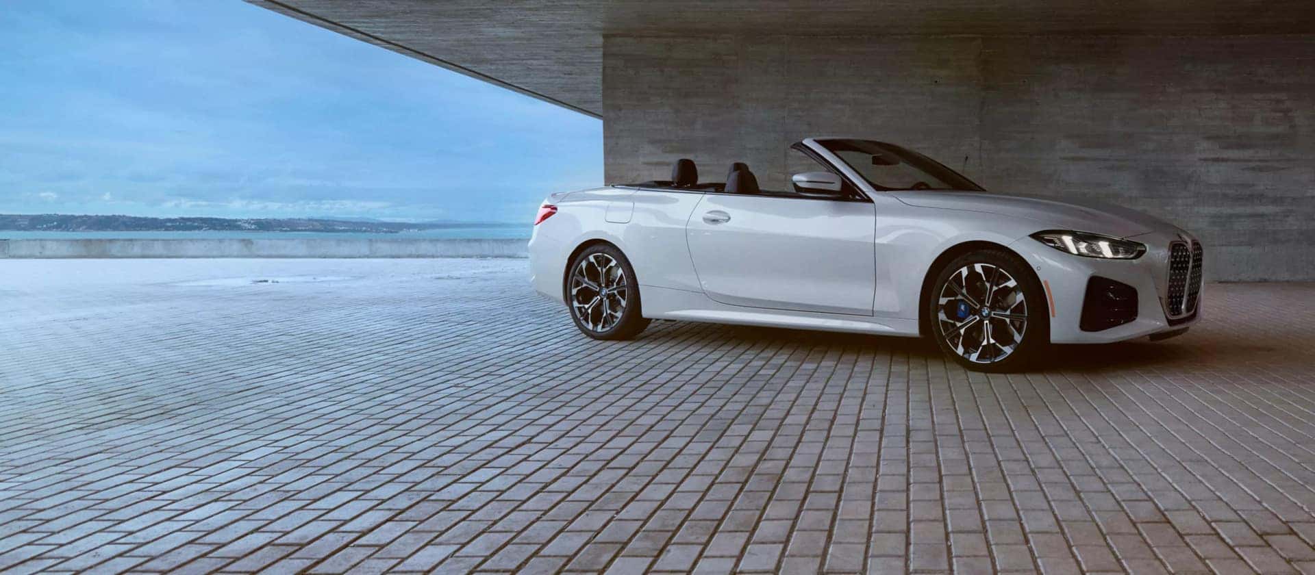 a white bmw 4 series convertible parked under a bridge