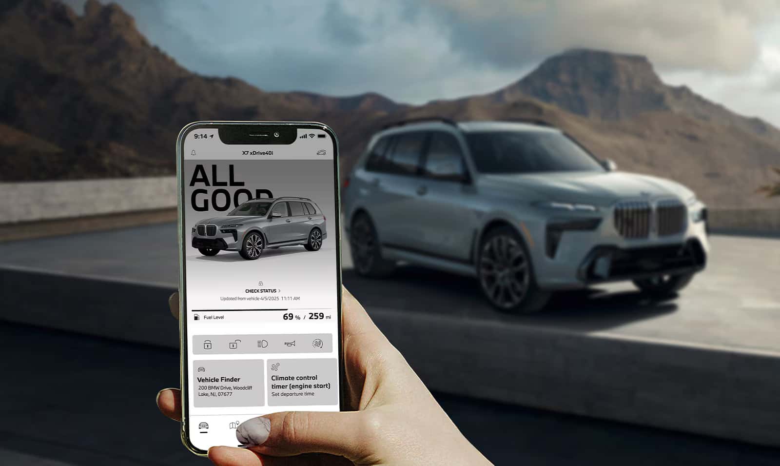 a person holding a smart phone with the myBMW app open and a bmw suv in driving in the background