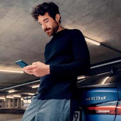 a man leaned on a 2026 bmw looking at the mybmw app going over critical information