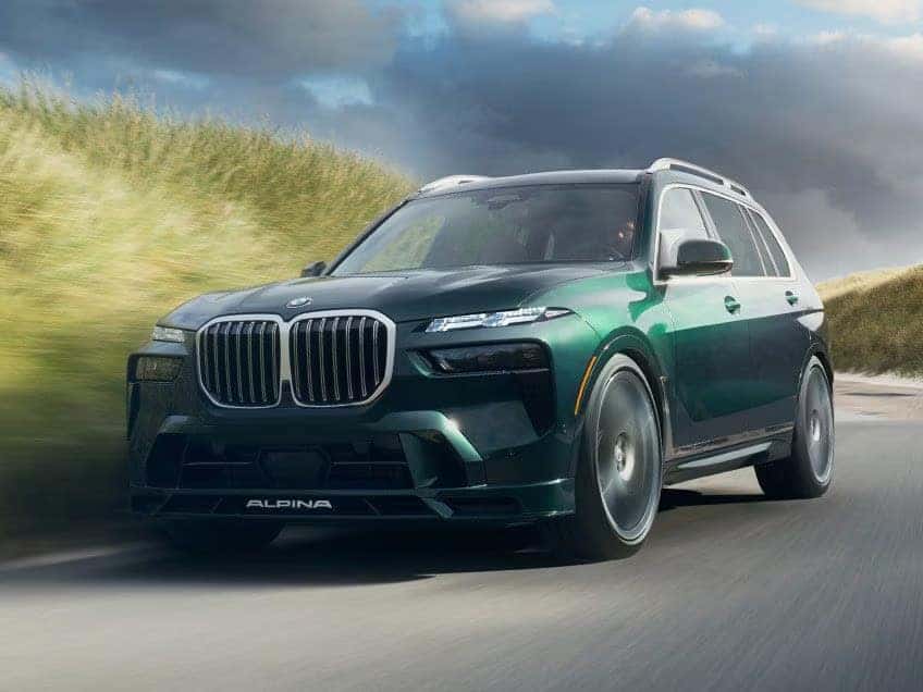 a 2026 BMW X7 Driving on a road next to a field