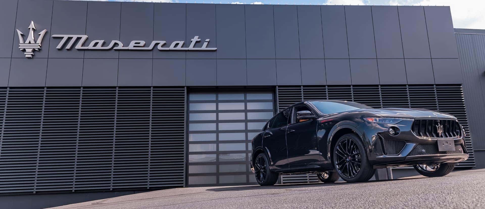 A man in a suit standing in front of a blue 2023 Maserati Quattroporte