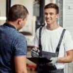 Service technician holding clipboard and talking to customer - Desert 215 Superstore Service