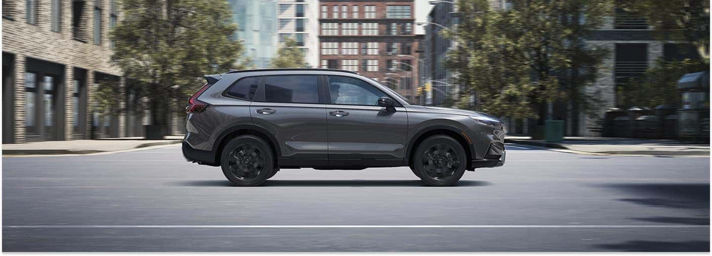 Side profile of a gray 2026 Honda CR-V driving on a city street.