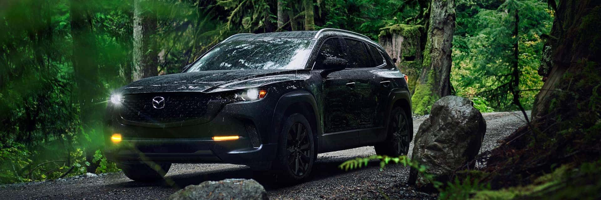 2026 mazda cx-50 driving in rain by trees