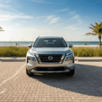 Silver Nissan Rogue parked at beach parking lot with palm trees and ocean view.