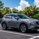 Grey Nissan Rogue SUV parked in a dealership lot on a sunny day.