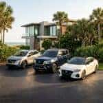 Three Nissan vehicles—a silver crossover, a blue SUV, and a white sedan—parked outside a modern beach house.