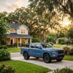 Blue pickup truck parked in the driveway of a suburban two-story house at sunset. (Representative image for illustration purposes only. Actual vehicle may vary based on trim and configuration.)