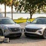 A silver Nissan Rogue and Hyundai Tucson parked outdoors near a river with people loading and unloading items. (Representative image for illustration purposes only. Actual vehicle may vary based on trim and configuration.)