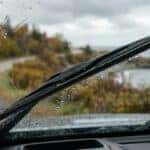 View through a rainy car windshield with a windshield wiper, overlooking a scenic coastal road in autumn. (Representative image for illustration purposes only. Actual vehicle may vary based on trim and configuration.)