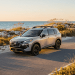 Silver Nissan SUV with a roof rack driving on a coastal road next to the ocean at golden hour. (Representative image for illustration purposes only. Actual vehicle may vary based on trim and configuration.)