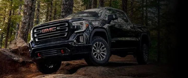 A GMC truck parked on top of a hill in a forest.