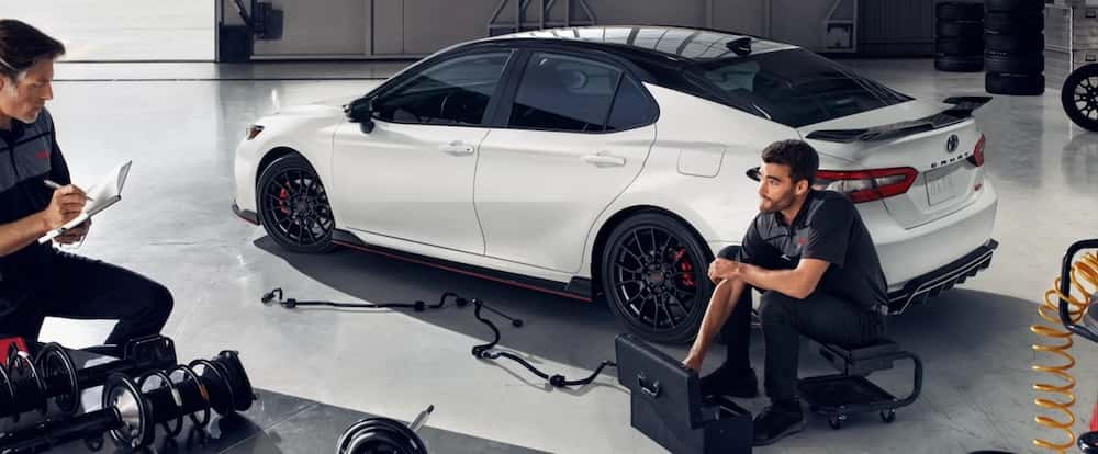Technicians servicing a white 2020 Toyota Camry
