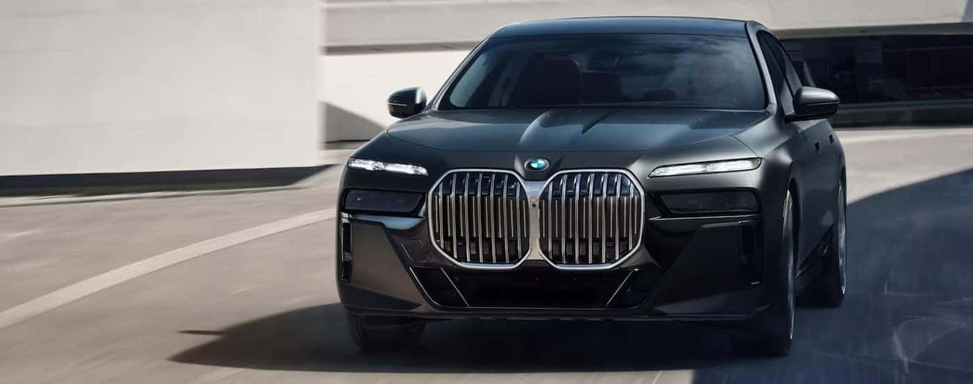 A black 2025 BMW 7 Series is shown driving on a sunny day.