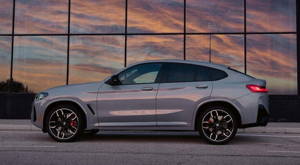 A gray 2025 BMW X4 is shown parked near a BMW dealer.