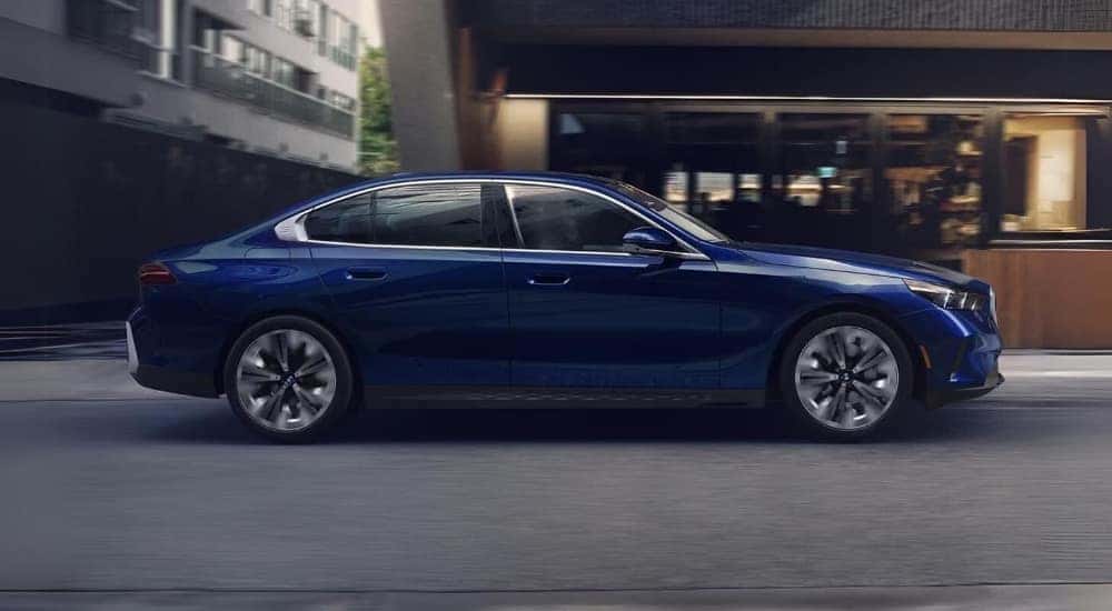 A blue 2024 BMW 5 Series is shown driving to a BMW dealer near you.