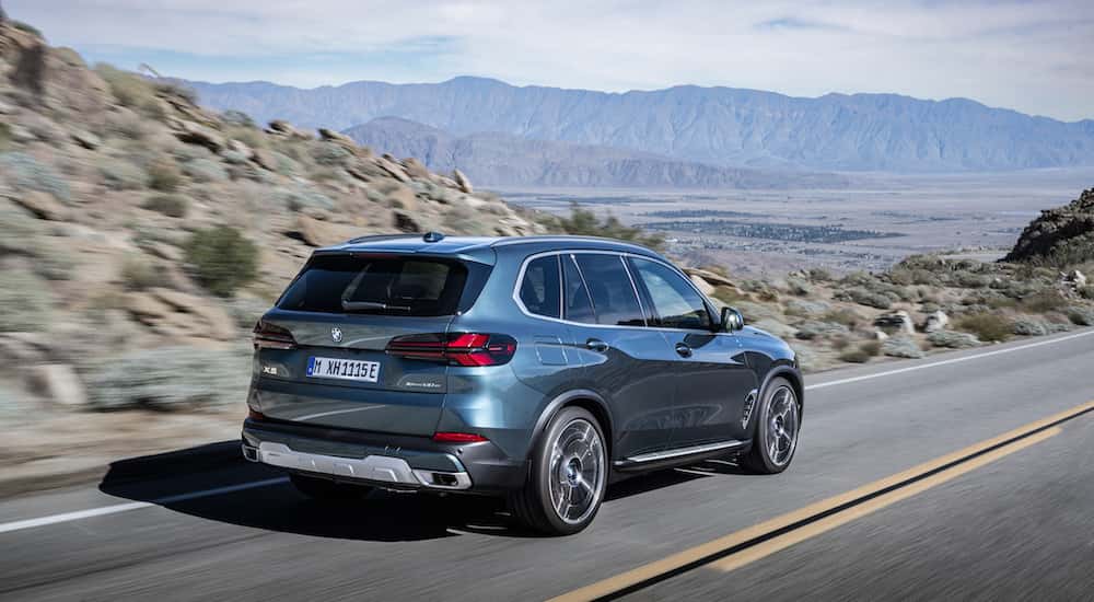 A blue 2025 BMW X5 for sale is shown from the rear at an angle.