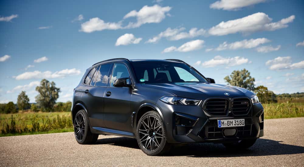 A blue 2025 BMW X5 M60i is shown from the front at an angle.