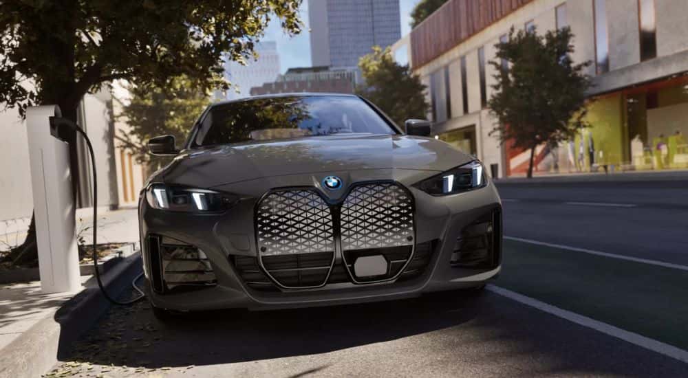 Head-on view of a grey 2025 BMW i4 eDrive40 charging at a public charging station.