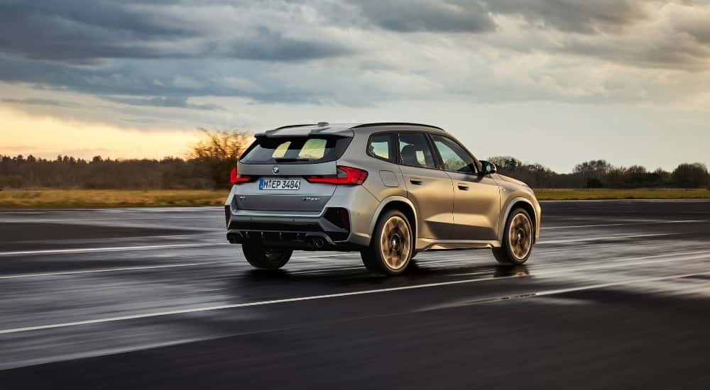 A silver 2025 BMW X1 M135i is shown from the rear at an angle.