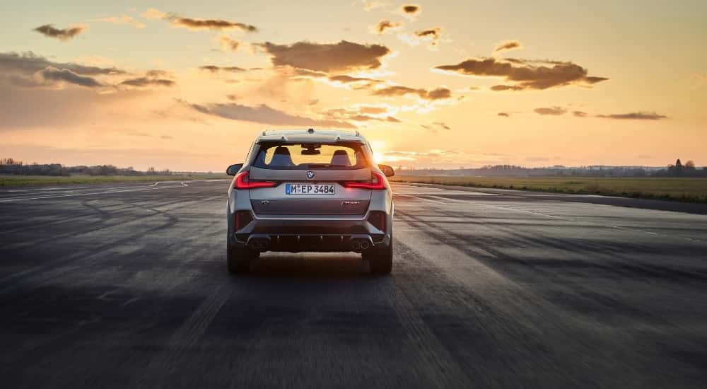 A silver 2025 BMW X1 M135i is shown from the rear.