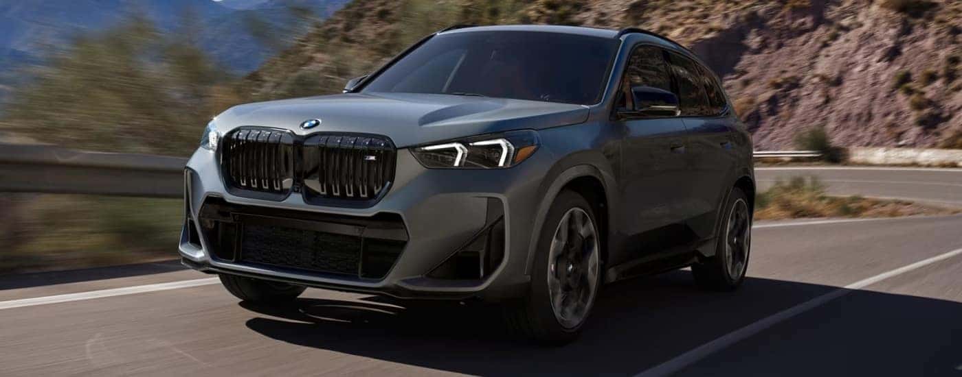 A grey 2024 BMW X1 M35i is driving round a corner.