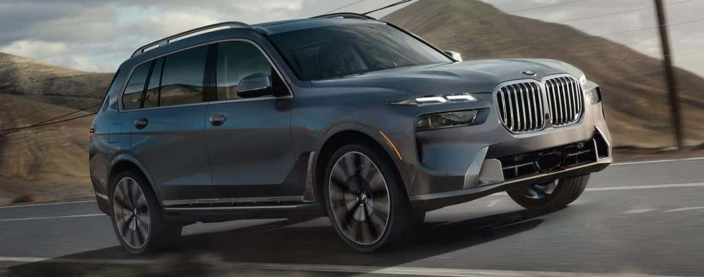 A gray 2026 BMW X7 for sale near Salem driving on a highway.