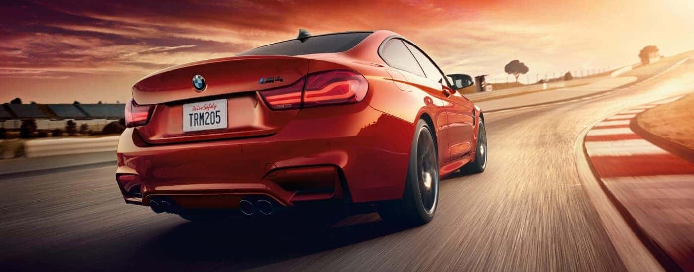 A red 2019 BMW M4 driving on a racetrack.