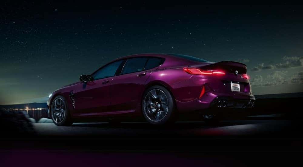 A purple 2022 BMW M8 Gran Coupe driving at night.