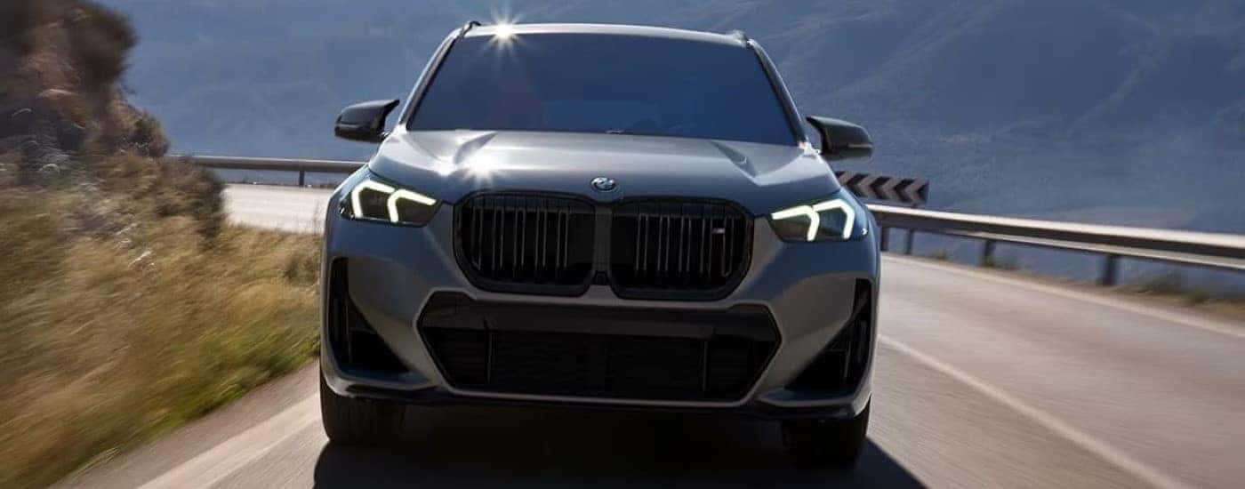A silver 2025 BMW X1 M35i is shown driving to a BMW dealer.