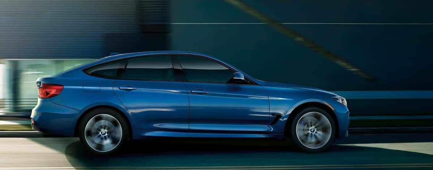 A blue 2019 used BMW 3 Series Gran Turismo for sale driving on a bridge.