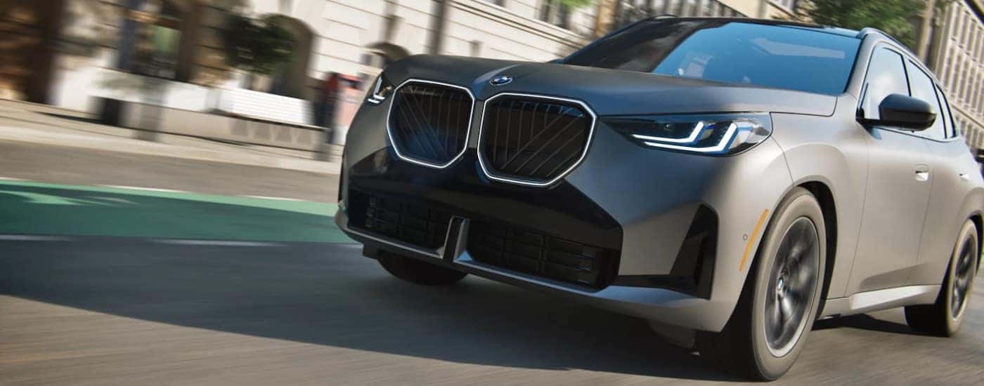 Grey 2025 BMW X3 for sale driving through a city.