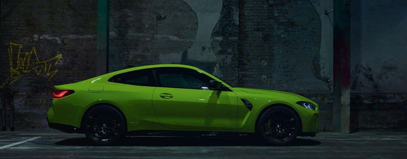 Green 2023 BMW M4 parked by a wall.