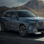 A silver 2026 BMW X7 parked on a hill.