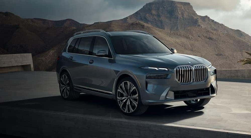 A silver 2026 BMW X7 parked near a hill